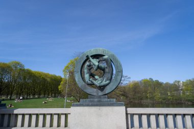 Oslo, Norveç - 3 Mayıs 2024: Vigeland Heykel Parkı 'nda, dairesel bir çerçeveye sarılmış bir çiftin bronz heykeli zarif bir şekilde duruyor. Bu sembolik parça hayat ve aşkın döngüsünü sembolize ediyor..