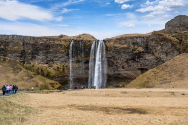 Seljalandsfoss Şelalesi, İzlanda - 5 Mayıs 2024: Turistler sisli bir ortamda yükselişe geçtiler.