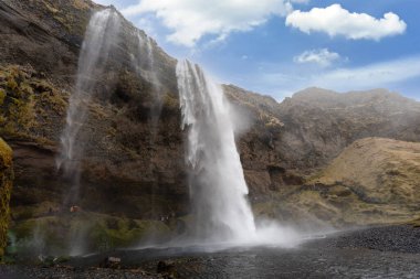 Görkemli Seljalandsfoss şelalesi buzulların eriyen sularından oluşur. Onu eşsiz yapan şelalenin arkasındaki ulaşılabilir iz. Reykjavik Yarımadası, İzlanda.