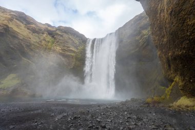 Görkemli Seljalandsfoss şelalesi buzulların eriyen sularından oluşur. Onu eşsiz yapan şelalenin arkasındaki ulaşılabilir iz. Reykjavik Yarımadası, İzlanda.