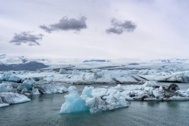 Mavi ve beyaz buzdağları buzul zeminine karşı buzul gölünde yüzerek huzur verici bir manzara yaratırlar. Bozulmamış Jokulsarlon, İzlanda.