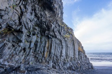 Reynisfjara 'nın dramatik bazalt sütunları siyah kumsal sahili için çarpıcı bir zemin oluşturur. Volkanik aktivitenin oluşturduğu bu yüksek uçurumlar, doğal güzelliğin bir anlık görüntüsünü sunuyor. Vik, İzlanda.