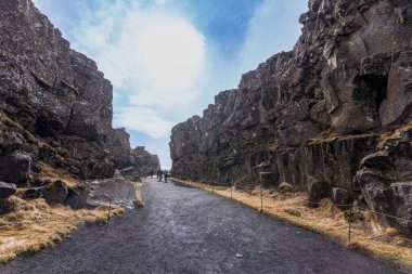 Kuzey Amerika ve Avrasya tektonik plakaları arasındaki ikonik yarık vadisiyle birlikte İzlanda 'daki Thingvellir Ulusal Parkı' nda bir yürüyüşçü yol boyunca yürür..