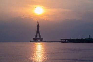 Tamsui Köprüsü 'nün inşaat halindeki görkemli bir silueti gün batımının altın renklerinde yıkanır. Bitmemiş yapı canlı bir gökyüzüne karşı dimdik ayakta duruyor. Tamsui, Tayvan.