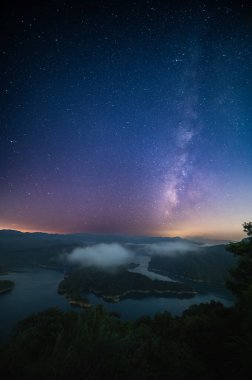 Nefes kesici bir gece gökyüzü Timsah Adası 'nda sakin bir gölü aydınlatıyor. Samanyolu ufuk boyunca uzanır ve dingin sulara ruhani parıltısını saçar. Yeni Tayvan Şehri, Tayvan.
