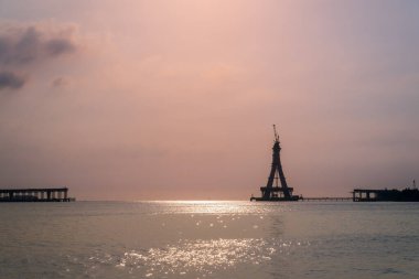 Tamsui Köprüsü 'nün inşaat halindeki görkemli bir silueti gün batımının altın renklerinde yıkanır. Bitmemiş yapı canlı bir gökyüzüne karşı dimdik ayakta duruyor. Tamsui, Tayvan.