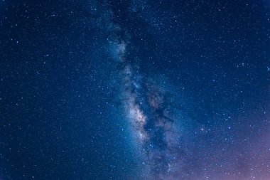 Sakin bir denizin üzerinde gece gökyüzüne uzanan Samanyolu 'nun nefes kesici bir görüntüsü. Galaksimizin yıldızlı kuşağı tüm ihtişamıyla görülebilir. Suao, Yilan County, Tayvan.