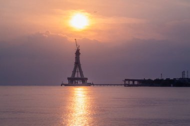 Tamsui Köprüsü 'nün inşaat halindeki görkemli bir silueti gün batımının altın renklerinde yıkanır. Bitmemiş yapı canlı bir gökyüzüne karşı dimdik ayakta duruyor. Tamsui, Tayvan.