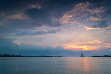 Tamsui Köprüsü 'nün inşaat halindeki görkemli bir silueti gün batımının altın renklerinde yıkanır. Bitmemiş yapı canlı bir gökyüzüne karşı dimdik ayakta duruyor. Tamsui, Tayvan.