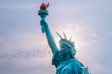 Özgürlük Anıtı 'nın bir kopyası batan güneşe karşı bir umut ışığı olarak duruyor. Heykelin meşalesi çevreyi aydınlatan sıcak bir ışık saçıyor. Shimen, New Taipei Şehri, Tayvan.