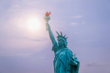 Özgürlük Anıtı 'nın bir kopyası batan güneşe karşı bir umut ışığı olarak duruyor. Heykelin meşalesi çevreyi aydınlatan sıcak bir ışık saçıyor. Shimen, New Taipei Şehri, Tayvan.