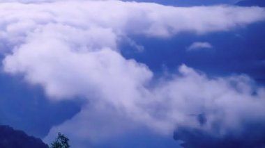 Hilal ay ve yıldızlı bir gece gökyüzünün altındaki bulutların nefes kesici panoramik görüntüsü. Uzak dağların silueti bu sakin manzaraya derinlik ve dram katıyor. Xindian, Tayvan.