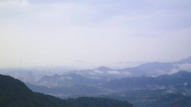 Yuvarlanan tepelerin sakin manzarası yemyeşil bitki örtüsüyle kaplı, bulutlardan oluşan bir deniz yukarda yavaşça sürükleniyor. Sisli atmosfer huzur ve huzur hissi yaratıyor. Xindian Bölgesi, Tayvan.