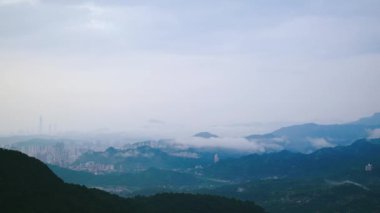 Bulutların arasından bakan uzak dağların olduğu sisli bir vadinin nefes kesici manzarası. Yeşillik ve yumuşak, doğal ışık güzel ve sakinleştirici bir sahne yaratır. Xindian, Tayvan.