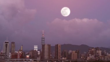 Taipei siluetinin üzerinde altın bir sonbahar ayı asılı, şehre sıcak bir parıltı saçıyor. Sahne, bir sonbahar akşamının sükunetini yakalar. Taipei Şehri, Tayvan.
