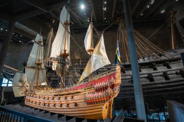 Stockholm, İsveç - 9 Mayıs 2024 Vasa savaş gemisinin özenle yeniden yaratılmış bir modeli 17. yüzyıl savaş gemisinin yanında duruyor. Oymalar ve renkler orjinal ihtişamına bir göz atıyor..