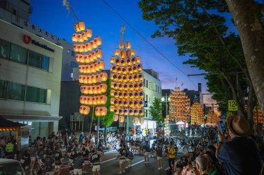 Akita, Japonya - 5 Ağustos 2024: Geleneksel kostümlü bir grup genç, canlı Akita Kanto Festivali sırasında sarı fenerler tutuyorlar. Sokaklar seyircilerle doluydu..