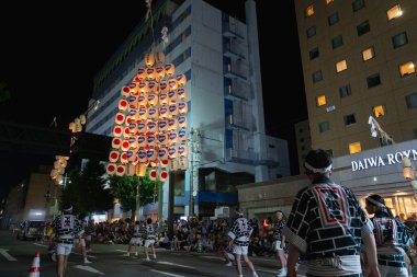 Akita Şehri, Japonya - 5 Ağustos 2024: Oyuncular uzun bambu direklerini çeşitli vücut parçalarında birden fazla fenerle dengeleyerek, yeteneklerini Akita Kanto Festivali 'nde sergilediler..