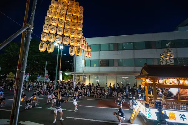 Akita, Japonya - 5 Ağustos 2024: Geleneksel kostümlü bir grup genç, canlı Akita Kanto Festivali sırasında sarı fenerler tutuyorlar. Sokaklar seyircilerle doluydu..