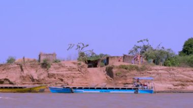 Bemaraha Ulusal Parkı, Madagaskar - 28 Ağustos 2024: Tsiribihina Nehri kıyısında yer alan geleneksel köy. Ahşap kulübeler ve ahşap tekneler manzarayı süslüyor..