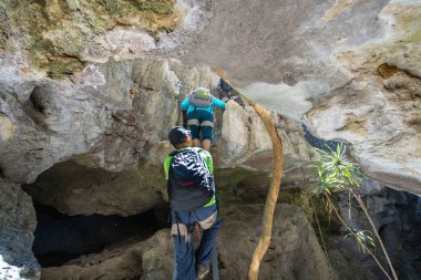 Bemaraha Ulusal Parkı, Madagaskar - 28 Ağustos 2024: Turistler derin bir vadi altında dar kireçtaşı mağaralarda gezinirler. Karst oluşumları ve ağaç kökleri eşsiz bir manzara yaratır..