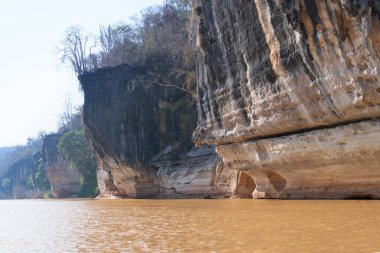 Eşsiz erozyon kalıpları ve yemyeşil bitki örtüsü olan kireçtaşı kayalıkları. Sarı nehir suyu boyunca kano gezisi. Manambolo Nehri, Madagaskar.