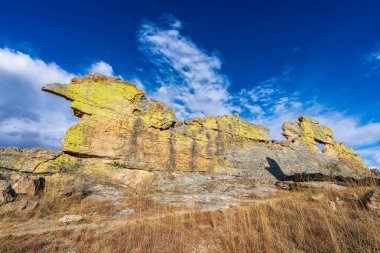 Canlı mavi gökyüzüne karşı sarı-yeşil liken ile kaplı canavar benzeri silueti olan yıpranmış kumtaşı uçurumları. Madagaskar 'daki Isalo Ulusal Parkı' nda popüler bir 