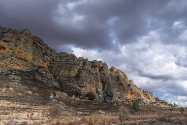 Görkemli kumtaşı kayalıkları ve katmanlı kaya oluşumları fırtınalı bir gökyüzüne karşı dramatik bir doğal manzara yaratır. Bu jeolojik oluşumlar Jurasik dönemde oluşmuştur. Madagaskar.
