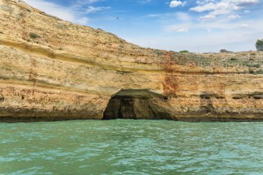 Alacakaranlıkta, zümrüt sularının üzerinde karmaşık deniz mağaralarıyla birlikte Altın Kıyı uçurumları yükseliyor. Dalgalar, Algarve ve Portekiz tarafından şekillendirilen şaşırtıcı kaya oluşumları.