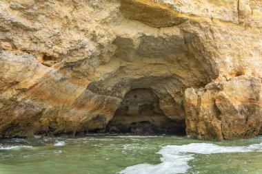 Karmaşık deniz mağaraları olan muhteşem sahil kayalıkları, altın ve kırmızımsı kaya oluşumlarının sergilendiği katmanlar. Turkuaz sular nefes kesici manzaraya ekleniyor. Algarve, Portekiz.