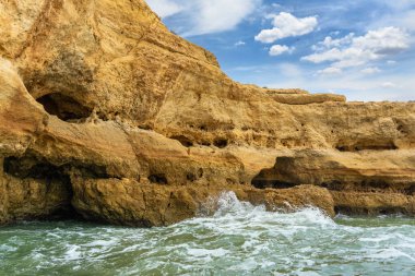 Alacakaranlıkta, zümrüt sularının üzerinde karmaşık deniz mağaralarıyla birlikte Altın Kıyı uçurumları yükseliyor. Dalgalar, Algarve ve Portekiz tarafından şekillendirilen şaşırtıcı kaya oluşumları.