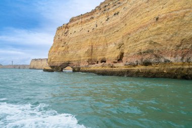 Karmaşık deniz mağaraları olan muhteşem sahil kayalıkları, altın ve kırmızımsı kaya oluşumlarının sergilendiği katmanlar. Turkuaz sular nefes kesici manzaraya ekleniyor. Algarve, Portekiz.