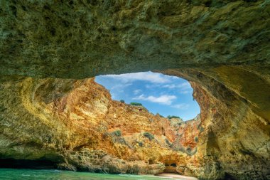 Benagil Mağarası 'ndaki tavan penceresinin nefes kesen manzarası doğal kaya oluşumlarını ve yukarıdaki mavi gökyüzünü gözler önüne seriyor. Bu ünlü deniz mağarası eşsiz güzelliğiyle bilinir. Algarve, Portekiz.