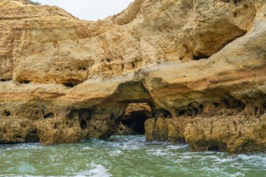 Alacakaranlıkta, zümrüt sularının üzerinde karmaşık deniz mağaralarıyla birlikte Altın Kıyı uçurumları yükseliyor. Dalgalar, Algarve ve Portekiz tarafından şekillendirilen şaşırtıcı kaya oluşumları.