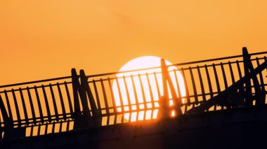 Canlı turist günbatımında Aşıklar Köprüsü 'nde siluetli turistler. Güneş köprünün arkasında batıyor, dramatik gölgeler bırakıyor. Tamsui Balıkçı Rıhtımı, New Taipei Şehri, Tayvan.