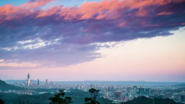 Bahar sabahının erken saatlerinde, Dajian Dağı 'ndan Taipei' nin nefes kesici manzarası. Altın güneş ışığı binaları yıkıyor. Gökyüzü pembe ve turuncu renklerden oluşan bir tuval. Xizhi, Tayvan.