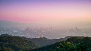 Dadong Dağı 'ndan gelen Pembe, turuncu ve mor renklerle dolu pastel renkli gökyüzü ile Taipei şehrinin puslu bir sabah manzarası. Huzurlu ve ruhani bir atmosfer yaratıyor. Dadong Dağı, Tayvan.