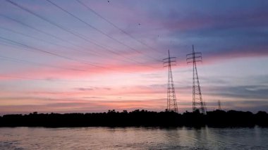 Nil Nehri üzerinde siluetli elektrik hatları ve kuleleri olan güzel bir günbatımı. Gökyüzü pembe, mor ve maviye boyanmıştır. Mısır, Nil Nehri 'ndeki bir gemiden alındı..