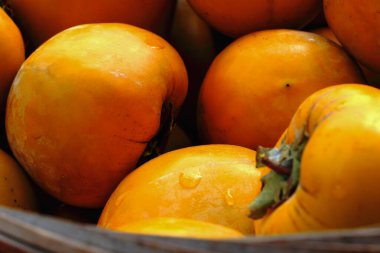 Soyulmadan önce içi canlı sarı-turuncu hurmalarla dolu bir sepetin yakın çekimi. Bu meyveler geleneksel hurma pastası yapmak için hazırlandı. Xinpu Kasabası, Hsinchu Bölgesi, Tayvan.