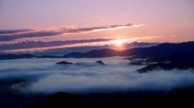 Tayvan 'daki Lion Head Dağı' ndan nefes kesici bir bahar gündoğumu. Güneş bulutların arkasından çıkar, sisli dağ zirvelerini aydınlatır..