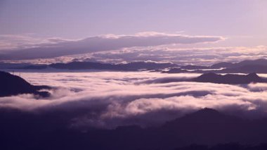 Tayvan 'daki Lion Head Dağı' nda sakin bir bahar şafağı. Turuncu gökyüzü beyaz bulutlarla buluşuyor, elektrik hattı kulelerinin siluetleri ile..