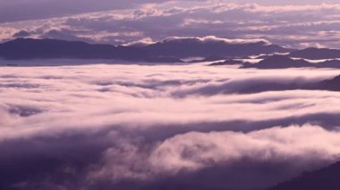 Tayvan 'daki Lion Head Dağı' nda sakin bir bahar şafağı. Turuncu gökyüzü beyaz bulutlarla buluşuyor, elektrik hattı kulelerinin siluetleri ile..