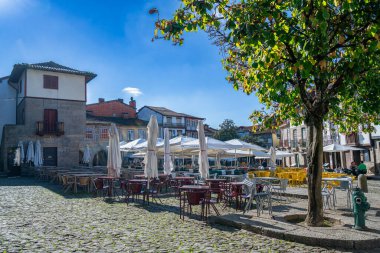 Amarante, Portekiz - 9 Kasım 2024: Açık hava yemeklerinin yer aldığı korunmuş tarihi mimariye sahip bir ortaçağ meydanı. Arazi kaldırım taşlarıyla çevrili, tuhaf eski binalarla çevrili..