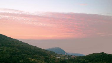 Datun Dağı 'nda bir bahar şafağı, Beitou, Tayvan, güneşin doğuşundan önce hafif güneş ışığıyla aydınlanan turuncu bulutları gözler önüne seriyor..