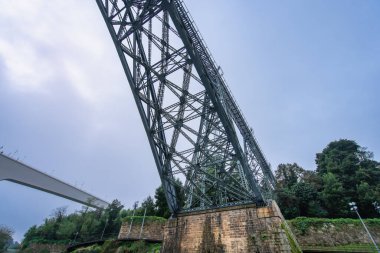 Porto ve Vila Nova de Gaia 'yı birbirine bağlayan Dom Luis Köprüsü' nün büyüleyici manzarası bulutlu bir öğleden sonra Douro Nehri 'nin altında akıyor..