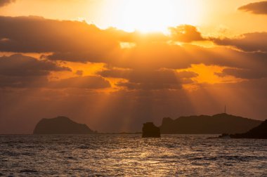 Jinshan, New Taipei, Tayvan 'da görkemli bir bahar gündoğumu. Altın güneş ışınları bulutları delip geçer, okyanusu aydınlatır ve Keelung Adası 'nı sıcak bir ışıltıyla aydınlatır..