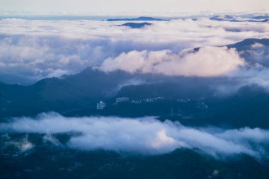 Tayvan, Xindian 'daki Lion' s Head Dağı 'nda sakin bir bahar sabahı, turuncu bir gökyüzü, hareket eden beyaz bulutlar ve siluetli güç kuleleri.