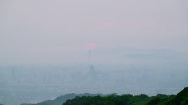 Shulin, New Taipei City, Tayvan 'daki Datun Dağı' ndan sisli bir alacakaranlık görüntüsü siluetli Taipei siluetinin portakal renginde kaybolduğunu ve kırmızı günbatımının sisin içinde kaybolduğunu gösteriyor..