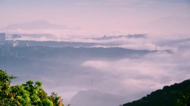 Tayvan 'ın New Taipei şehrinde bulunan Datun Dağı' nın sisli tepelerinde beyaz bulutlar yavaşça süzülüyor. Güç iletim kuleleri sislerin arasından kolayca görülebiliyor..
