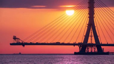 Gün batımında inşa edilen köprü Tayvan 'da sakin bir nehrin üzerinde canlı günbatımı bulutları ile.